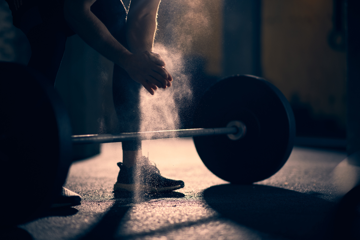 Lifter chalking up over a loaded barbell