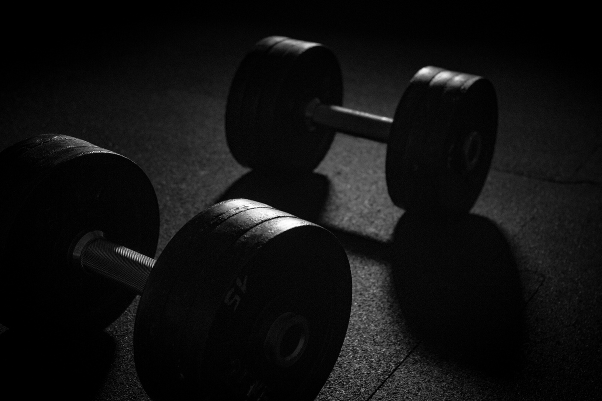 Rubber dumbbells resting on a dark gym floor